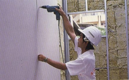 施工人員以電動起子鎖固輕隔間封板